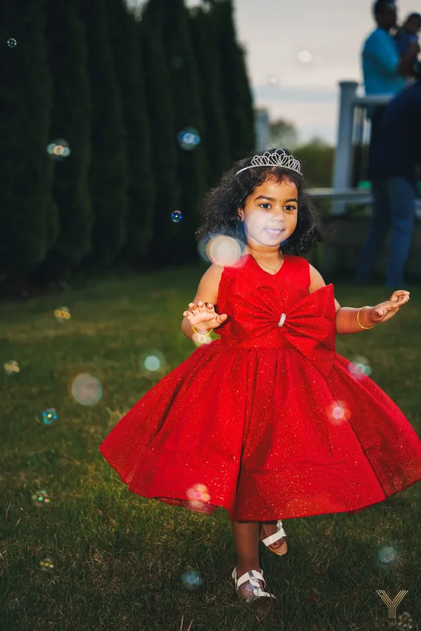 Girl in a red dress dancing through bubbles